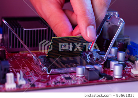 A man's hand inserts a processor into the motherboard chipset A man's hand inserts a processor into the motherboard chipset 93661835