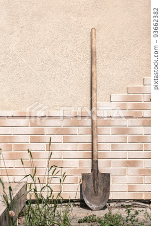 Old dirty filthy shovel against the tile wall summer day 93662382