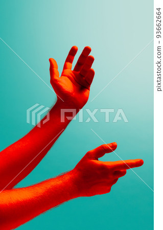 Pointing. Authentic hands gesturing isolated on cyan color background in red neon light. Concept of relationship, community, care, support, symbolism, culture 93662664