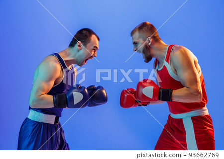 Sports emotions. Excited professional boxers in red and blue sports uniform boxing isolated on blue background in neon light. Sport, skills, power, training, energy Sports emotions. Excited professional boxers in red and blue sports uniform boxing isolated on blue background in neon light. Sport, skills, power, training, energy 93662769
