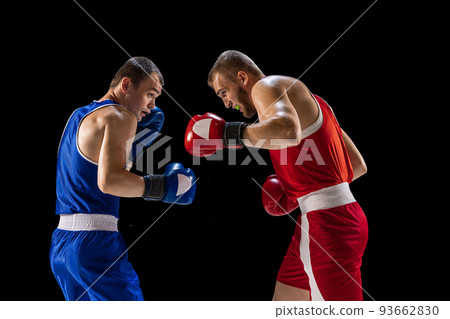 Young men, professional boxers in red and blue sports uniform boxing isolated on dark background. Concept of sport, skills, power, training, energy 93662830