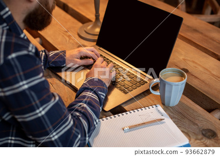 Cropped image of young man chatting via net-book during work break in coffee shop, male sitting in front open laptop computer with blank copy space screen. Cropped image of young man chatting via net-book during work break in coffee shop, male sitting in front open laptop computer with blank copy space screen. 93662879