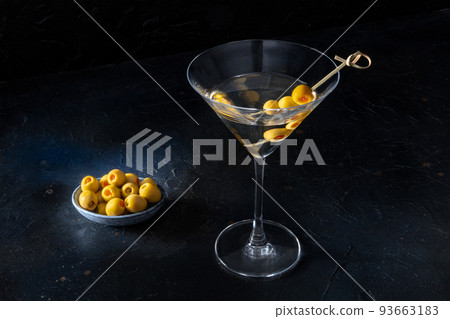 Martini, a glass with spicy olives on a toothpick, on a black background 93663183