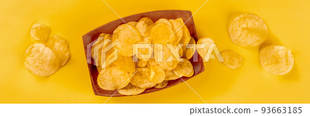 Potato chips or crisps, a salty snack on a wooden background, a panorama 93663185