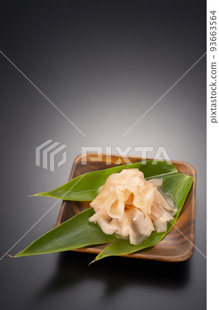 A black background shot of sweet pickled ginger on a wooden plate A black background shot of sweet pickled ginger on a wooden plate 93663564