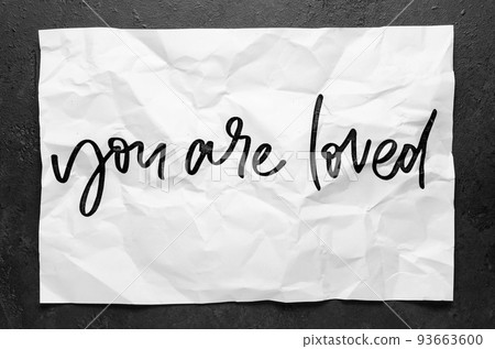 You are loved. Lettering on crumpled white paper. Handwritten text. Inspirational quotes. You are loved. Lettering on crumpled white paper. Handwritten text. Inspirational quotes. 93663600