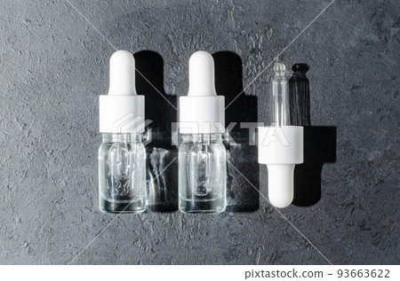 Cosmetic product in a bottle with a pipette. Serum for skin or hair. Black concrete background. 93663622