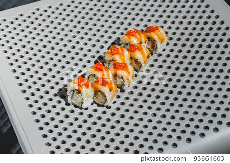 Sushi rolls with eel, shrimp, cucumber and cream cheese, decorated with red caviar. Hard light, deep shadow 93664603