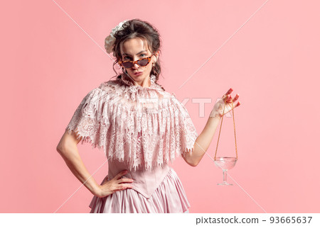 Rights. One young fashionable woman with retro style hairdo wearing medieval dress posing isolated on pink background. Eras comparison concept 93665637
