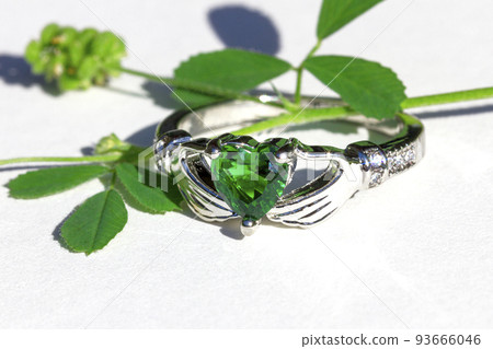 Claddagh ring with green emerald. Traditional Irish ring in shape of two hands holding a heart shaped green gemstone. Claddagh ring with green emerald. Traditional Irish ring in shape of two hands holding a heart shaped green gemstone. 93666046