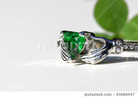 Claddagh ring with green emerald. Traditional Irish ring in shape of two hands holding a heart shaped green gemstone. Claddagh ring with green emerald. Traditional Irish ring in shape of two hands holding a heart shaped green gemstone. 93666047
