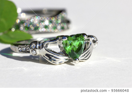 Claddagh ring with green emerald. Traditional Irish ring in shape of two hands holding a heart shaped green gemstone. Claddagh ring with green emerald. Traditional Irish ring in shape of two hands holding a heart shaped green gemstone. 93666048