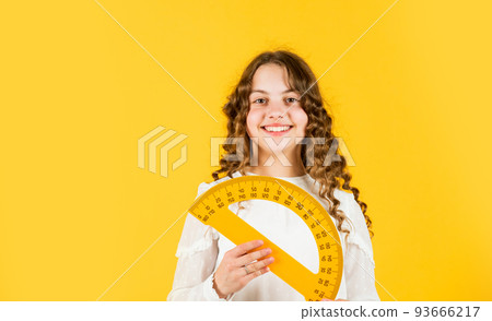 Measure angles in degrees. School lessons. Adorable cute pupil. She loves studying. Small girl holding protractor for geometry lesson. Back to school. Student learning geometry yellow background 93666217