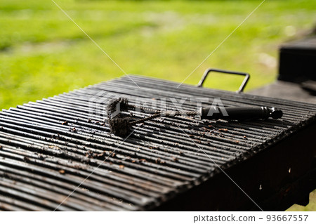 outdoor barbeque grill with black brush tool for cleaning on top 93667557