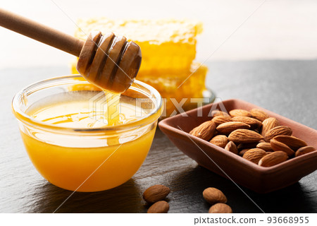 Slate tray with honey almonds and honeycomb on kitchen table 93668955