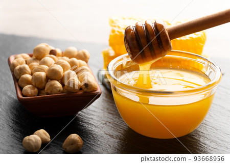 Slate tray with honey hazelnuts and honeycomb on kitchen table 93668956