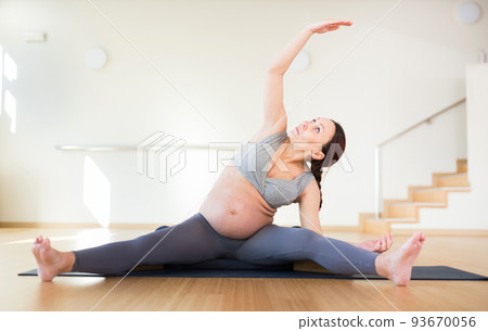 Pregnant woman is engaged in yoga. Revolved seated side angle pose or Parivrtta Upavistha Konasana 93670056