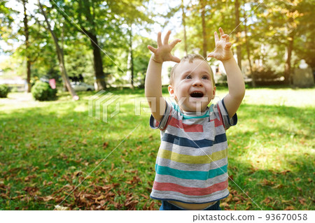 Happy toddler boy playing in the park on a sunny day. Smile boy of one and a half years outdoors. Cheerful childhood. Selective focus 93670058
