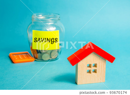 Wooden house and glass jar with money Savings. Real estate concept. Family budget planning. Investments, plans, savings. Mortgage and mortgage rates. Forecasts. Loan. Refinance home Wooden house and glass jar with money Savings. Real estate concept. Family budget planning. Investments, plans, savings. Mortgage and mortgage rates. Forecasts. Loan. Refinance home 93670174