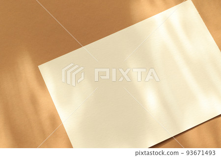 empty white paper sheet on brown background with sunlight glow and shadows 93671493
