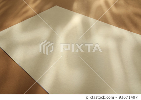 empty white paper sheet on brown background with sunlight glow and shadows empty white paper sheet on brown background with sunlight glow and shadows 93671497