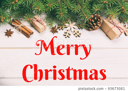 Merry Christmas text. Christmas background with fir tree and gift box on wooden table. Top view with copy space for your design. Toned Merry Christmas text. Christmas background with fir tree and gift box on wooden table. Top view with copy space for your design. Toned 93673081