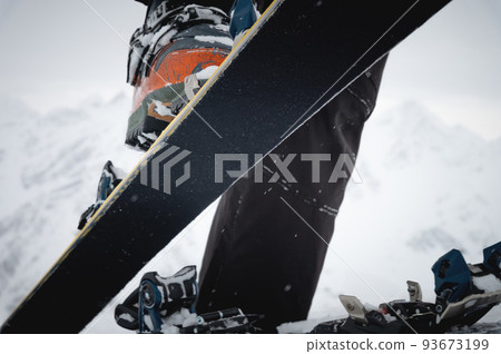 Close-up of a man's hand, adjusting the skis against the background of snow and things, putting on the skins on the track. Ski touring theme in the mountains 93673199