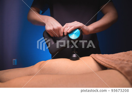 Masseur massaging legs with massage percussion device in spa center to muscular patient athlete Masseur massaging legs with massage percussion device in spa center to muscular patient athlete 93673208