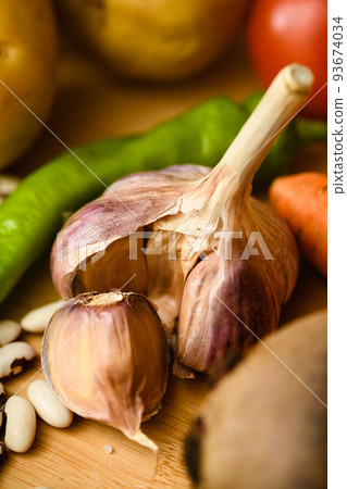 Close-up of young, fresh garlic on a wooden cutting board. Close-up of young, fresh garlic on a wooden cutting board. 93674034