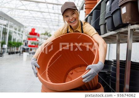Satisfied woman working in plant pot department at garden store 93674062