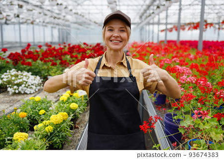 Portrait of satisfied female florist greenhouse worker showing thumbs up 93674383