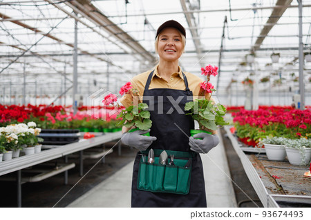 Pretty caucasian woman with flowers in her hands at greenhouse 93674493