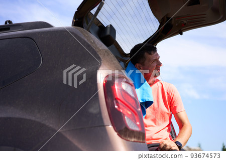 Sportsman wiping sweat with a towel sitting in trunk outdoors. 93674573