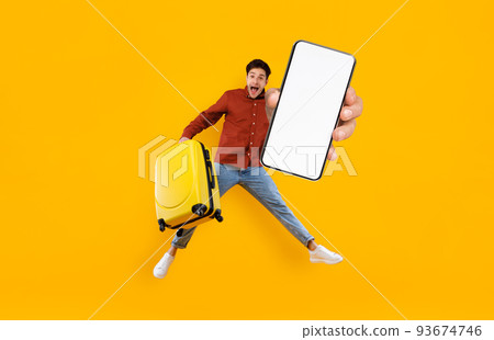 Excited Tourist Guy Jumping With Luggage And Showing Big Blank Smartphone Excited Tourist Guy Jumping With Luggage And Showing Big Blank Smartphone 93674746