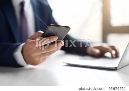 Unrecognizable Male Entrepreneur Using Smartphone And Working With Laptop In Office 93674751