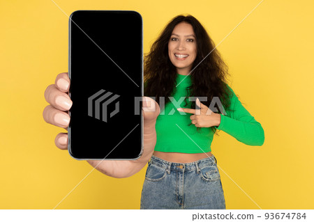 Cheerful Middle Eastern Lady Showing Big Phone Screen, Yellow Background Cheerful Middle Eastern Lady Showing Big Phone Screen, Yellow Background 93674784