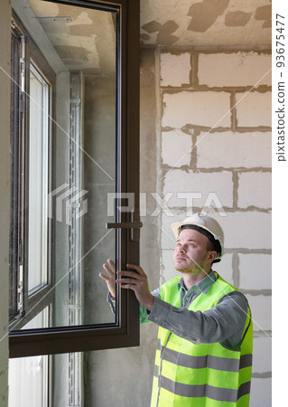 male chief engineer in the room make measurements of windows, specialists in the installation and replacement of double-glazed windows. male chief engineer in the room make measurements of windows, specialists in the installation and replacement of double-glazed windows. 93675477