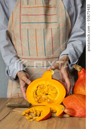 woman cuts orange pumpkins with a knife on a cutting board in the kitchen. cooking pumpkin is an eco-friendly food for the whole family woman cuts orange pumpkins with a knife on a cutting board in the kitchen. cooking pumpkin is an eco-friendly food for the whole family 93675483