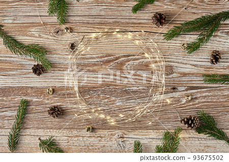 Christmas composition with fir tree branches and lighting garland on wooden background. Christmas frame, flat lay. Xmas greeting banner with copy space Christmas composition with fir tree branches and lighting garland on wooden background. Christmas frame, flat lay. Xmas greeting banner with copy space 93675502