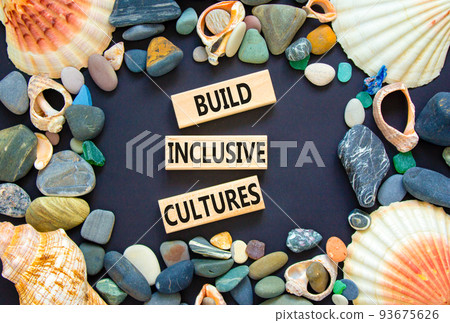 Build inclusive cultures symbol. Concept words Build inclusive cultures on wooden blocks. Beautiful black background. Sea stones and sea shells. Business build inclusive cultures concept. Copy space. 93675626