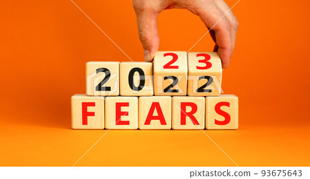 2023 fears new year symbol. Businessman turns a wooden cube and changes words Fears 2022 to Fears 2023. Beautiful orange background, copy space. Business 2023 fears new year concept. 2023 fears new year symbol. Businessman turns a wooden cube and changes words Fears 2022 to Fears 2023. Beautiful orange background, copy space. Business 2023 fears new year concept. 93675643
