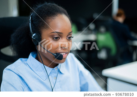 African young woman talking to a client on a headset. Female employee of the call center. African young woman talking to a client on a headset. Female employee of the call center. 93678010