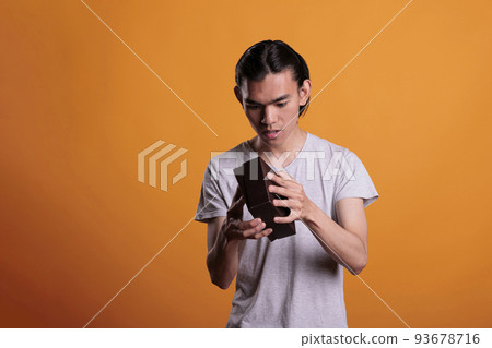 Curious asian man opening gift, looking inside small cardboard box, unboxing present. Young person unpacking surprise, holding delivery parcel with interested facial expression 93678716