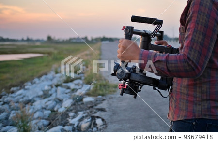 Camera technician working on a gimbal When shooting movies on a small set, use both hands to hold the stabilizer attachment for a smooth video. 93679418