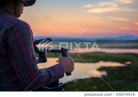 Camera technician working on a gimbal When shooting movies on a small set, use both hands to hold the stabilizer attachment for a smooth video. Camera technician working on a gimbal When shooting movies on a small set, use both hands to hold the stabilizer attachment for a smooth video. 93679419