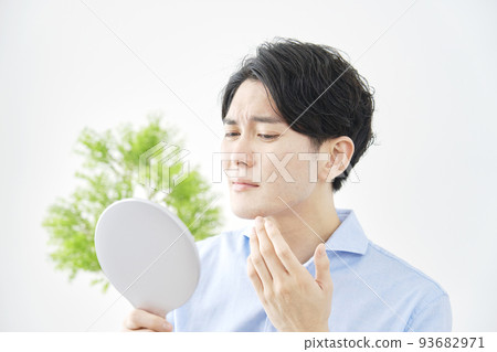 A man checking his face in the mirror at home 93682971