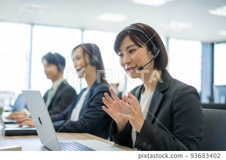 Woman doing customer support while wearing a headset at a call center Woman doing customer support while wearing a headset at a call center 93683402