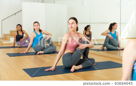 Girl sitting in twisting asana Matsyendrasana during yoga class Girl sitting in twisting asana Matsyendrasana during yoga class 93684045