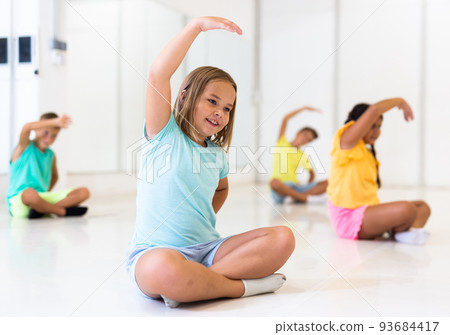 Little girl doing stretching exercises before training in dance class 93684417