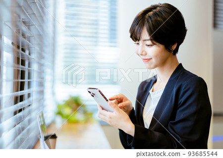 A woman operating a smartphone in the office A woman operating a smartphone in the office 93685544